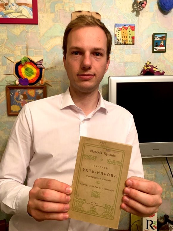 Сергей Тамби с книгой Л. А. Рюне под названием «Морские купания: Курорт Усть-Нарова (Гунгенбург и Шмецке): краткое иллюстрированное описание с приложением плана, списка сдающихся дач, таксы для приезжающих и пр». (Нарва, 1912).